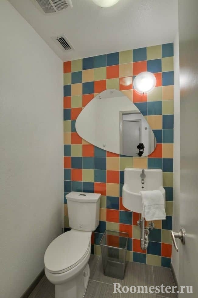 Μικρή τουαλέτα με φωτεινά πλακάκια και ζωγραφισμένους τοίχους