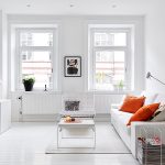White sofa with orange pillows in front of the TV