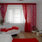 Röda gardiner, kuddar och matta i kombination med vita väggar och möbler