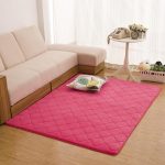 Rožinis kilimas šalia baltos sofos