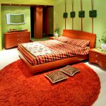 Kalkgrønne vegger og oransje teppe på soverommet