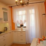 Murs orange et meubles blancs dans la cuisine