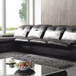 Μαύρος καναπές με φωτεινά μαξιλάρια στο δωμάτιο