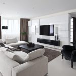 Lys sofa og svart lenestol i stuen