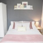 Rožinė lovatiesė pilkame miegamajame