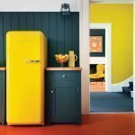 Die Kombination aus grauer Wand und gelbem Kühlschrank