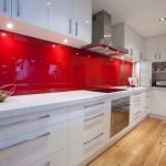 Hvide møbler og rødt forklæde i det indre af køkkenet