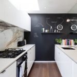 Balti baldai ir juodos sienos virtuvėje