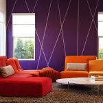 Połączenie liliowych ścian i pomarańczowej sofy