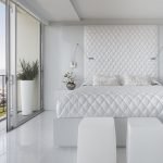 Hvid seng i soveværelset med et stort vindue