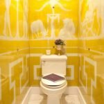 Κίτρινο πλακάκι με λευκό στολίδι στην τουαλέτα