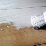 Melukis cat putih di atas permukaan kayu